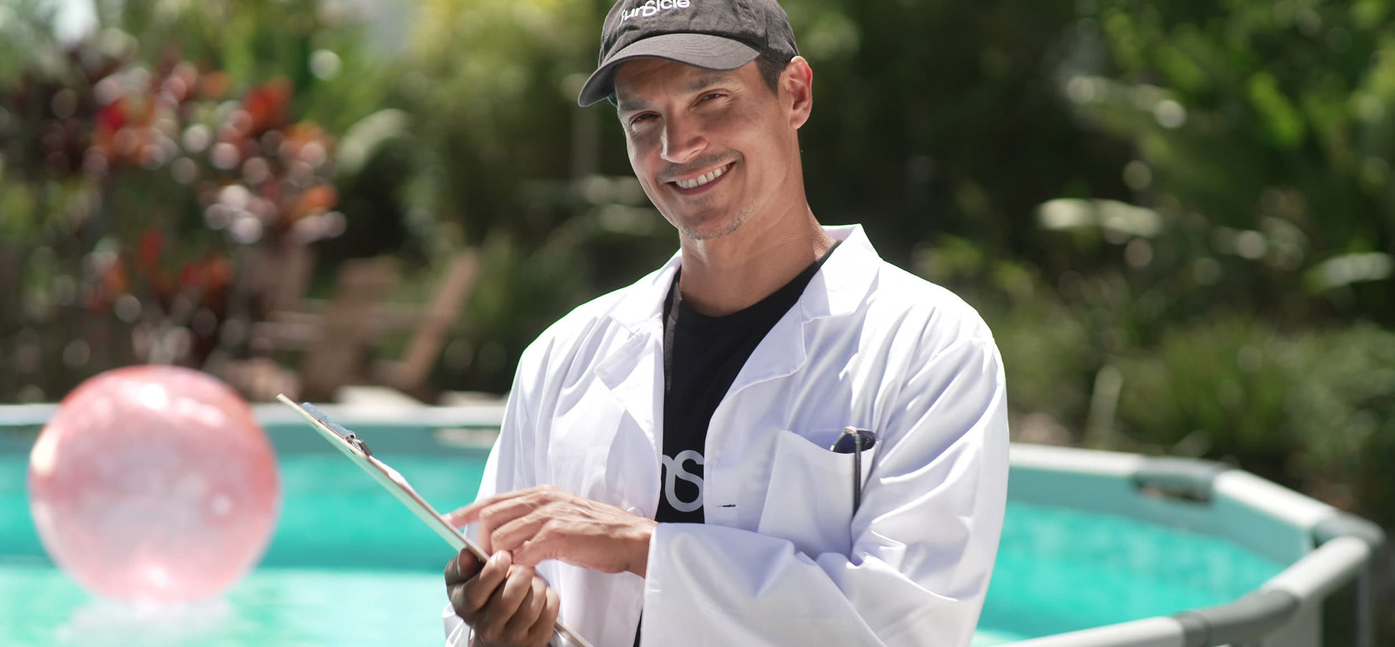 a smiling man with lab coat holding a clipboard with Funsicle Oasis Pool in the background