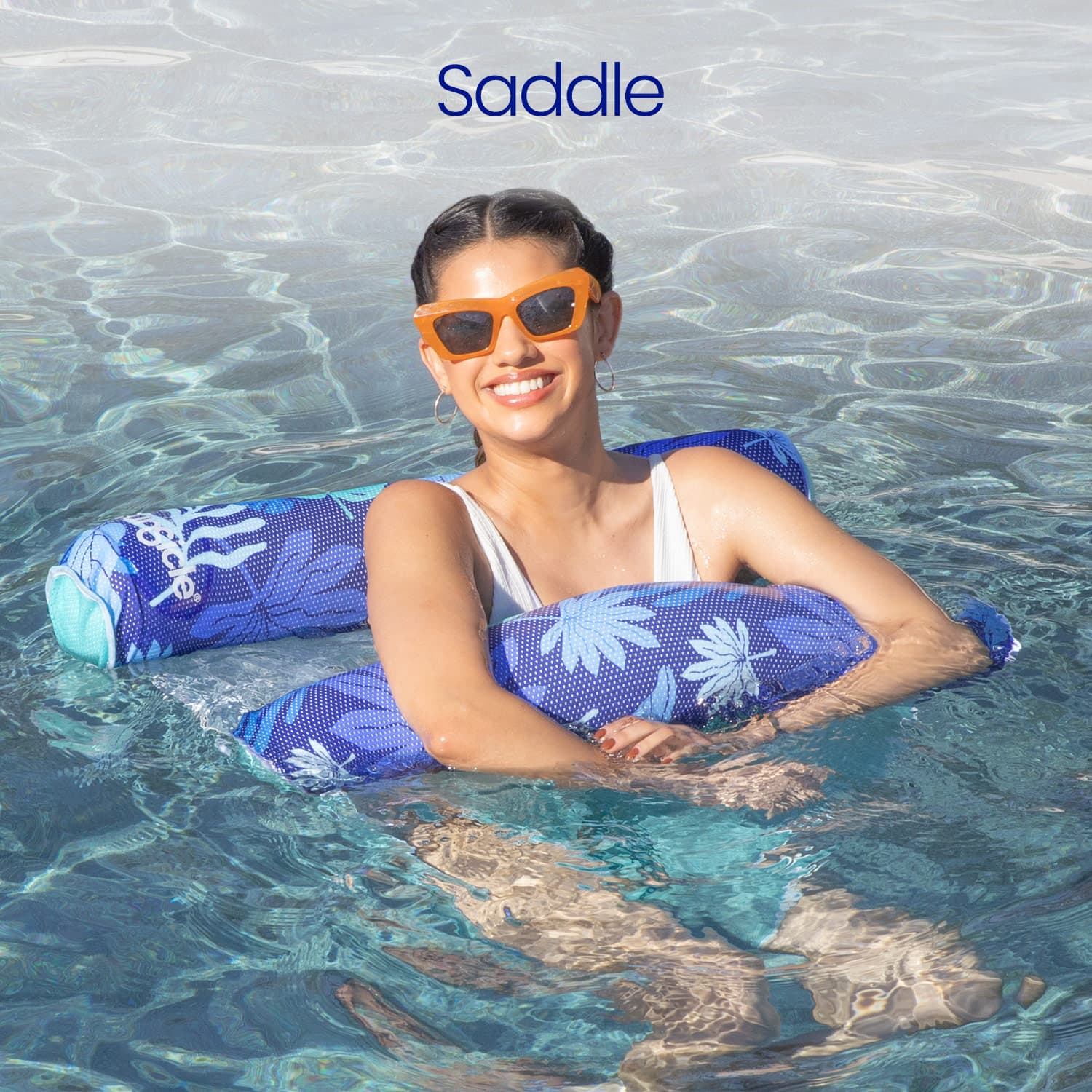 Woman in a pool with a blue floral-patterned floatie, wearing sunglasses.