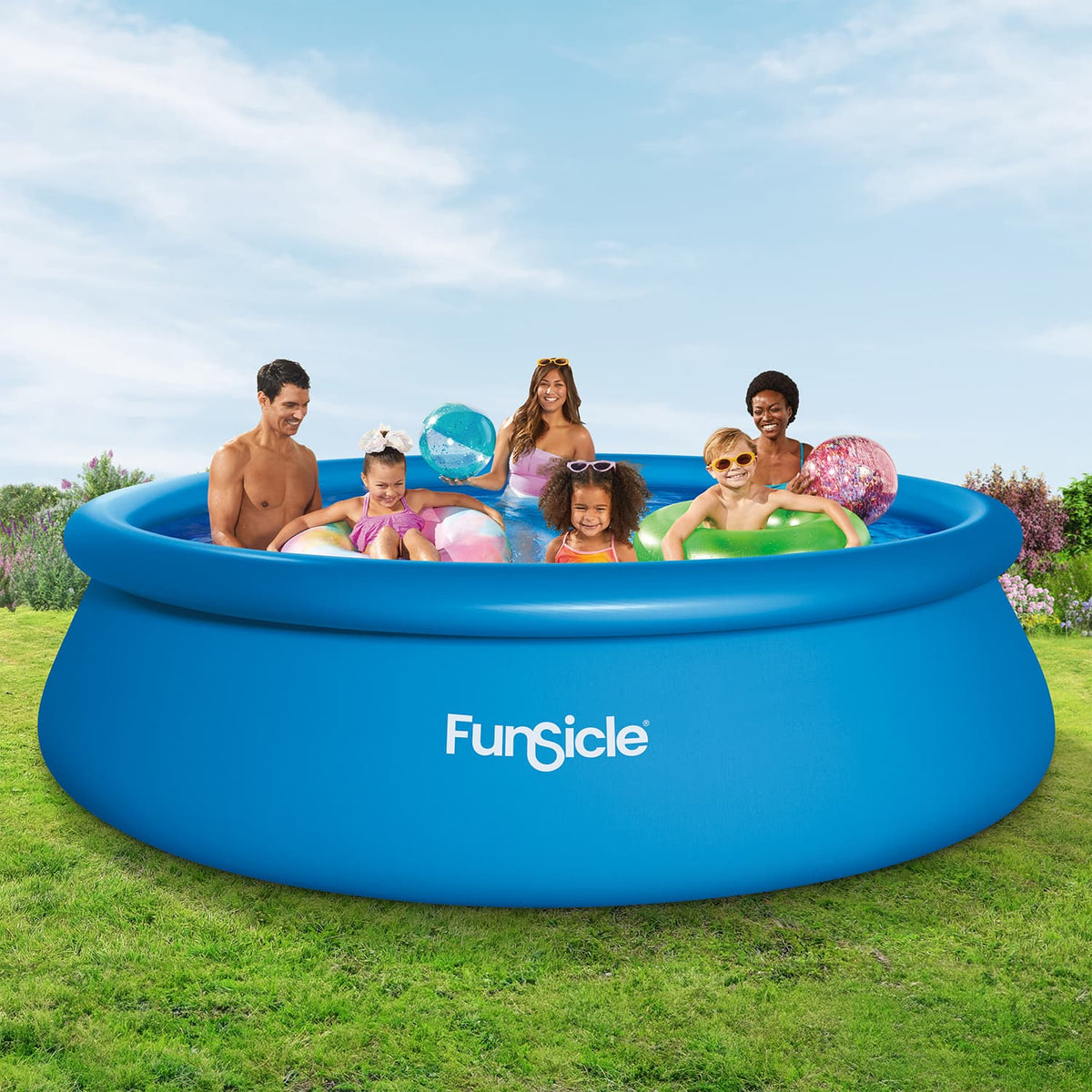 Six people enjoy swimming and playing with colorful inflatable beach balls and pool floats in a blue Funsicle QuickSet Pool on a grassy backyard lawn.