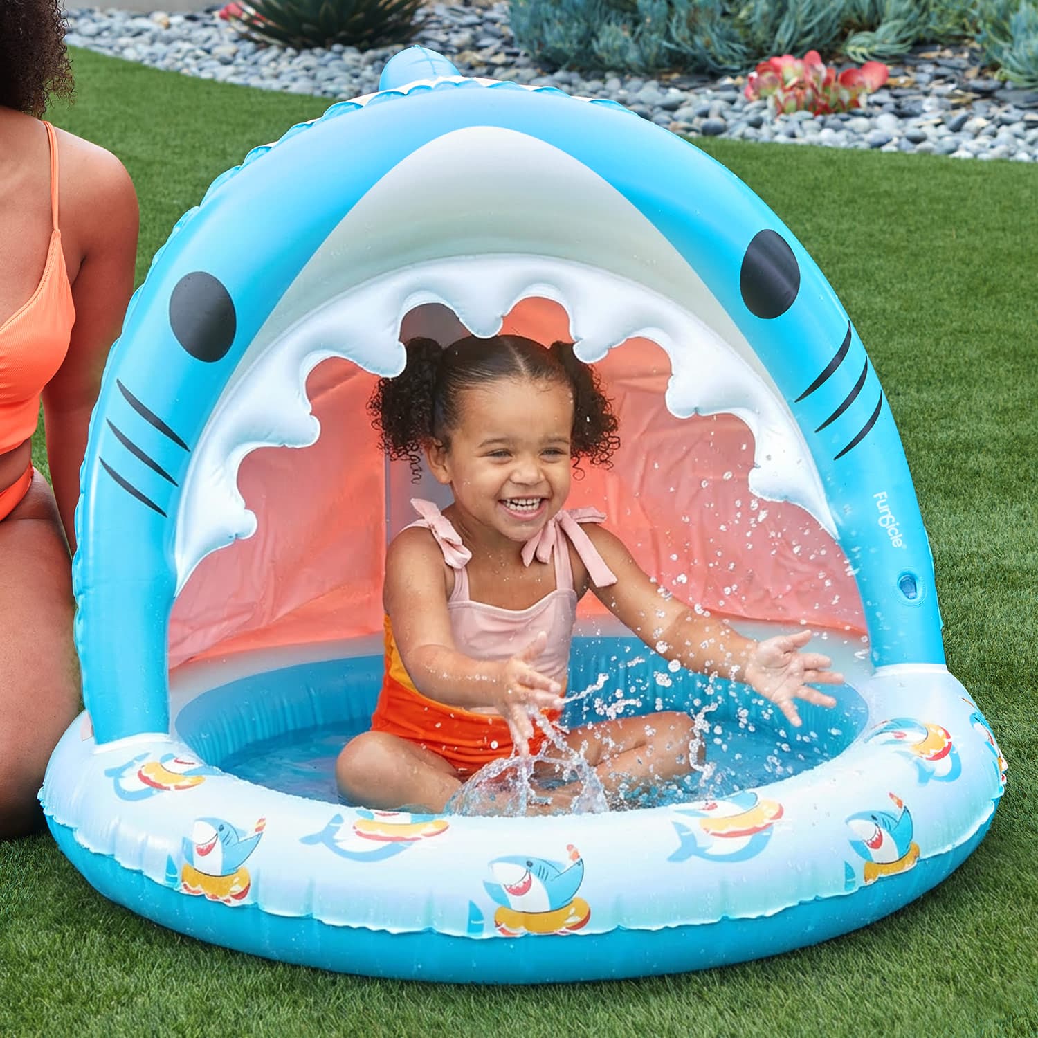 Child playing in a shark-shaped inflatable pool on grass