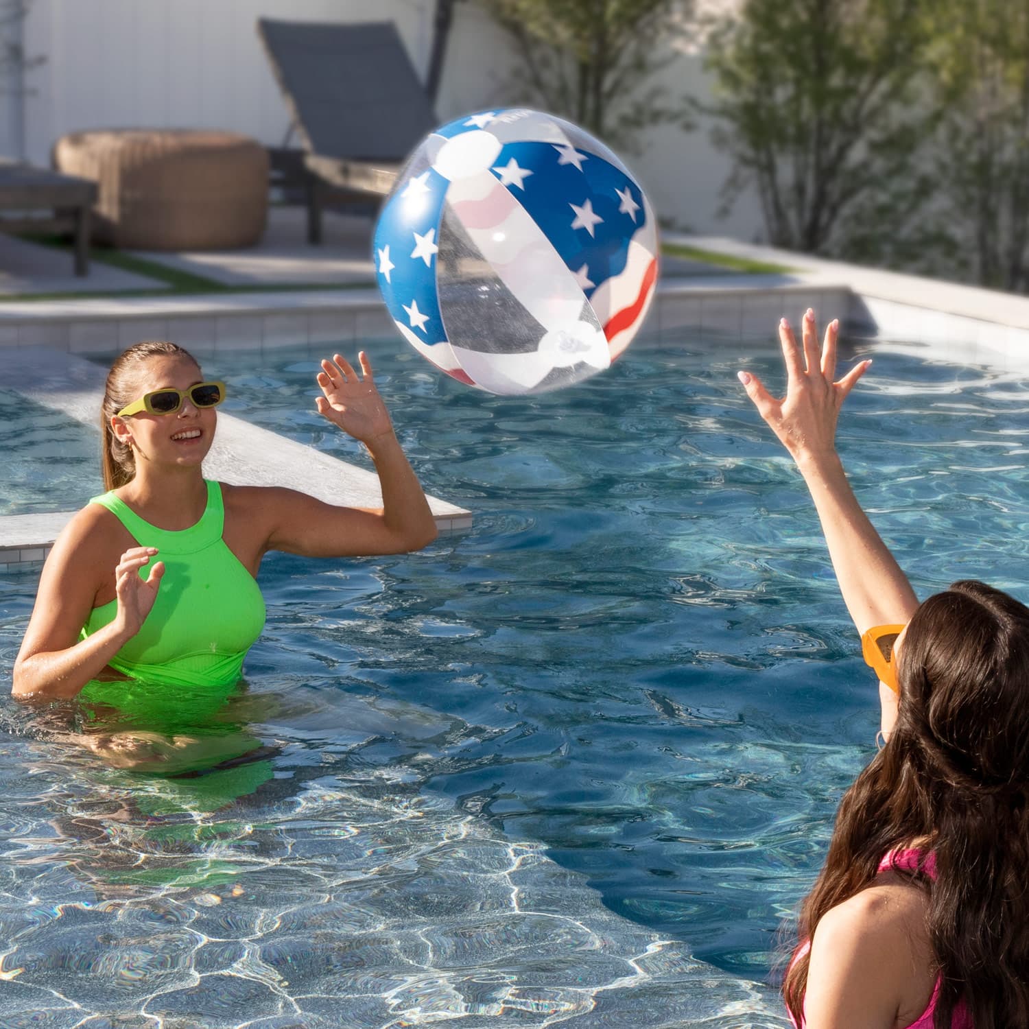 Two women playing with a beach ball in a pool