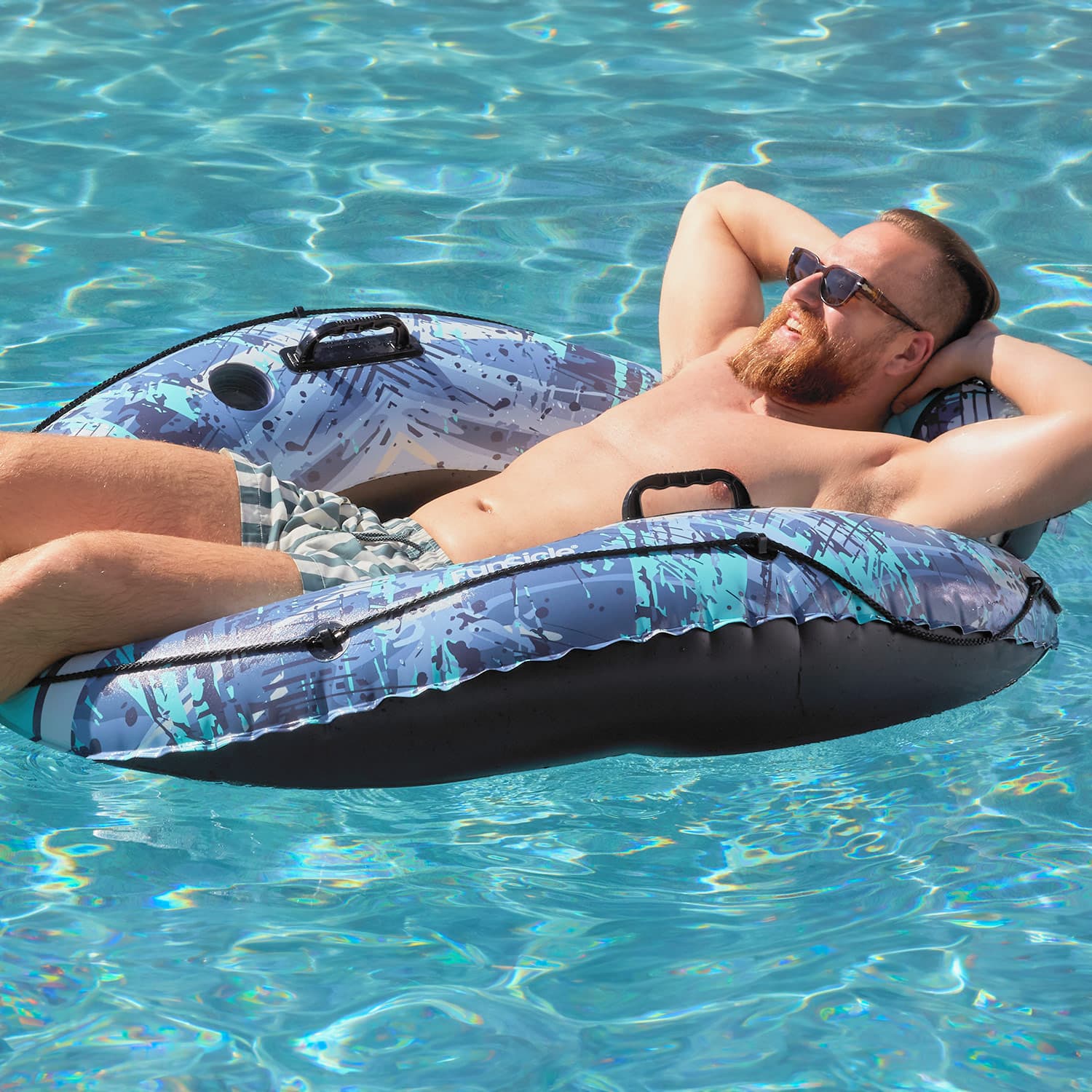 Man relaxing on a patterned inflatable tube in clear blue water
