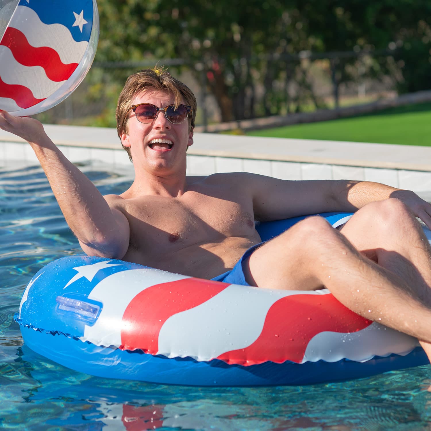 Man lounging on a patriotic inflatable ring in a pool