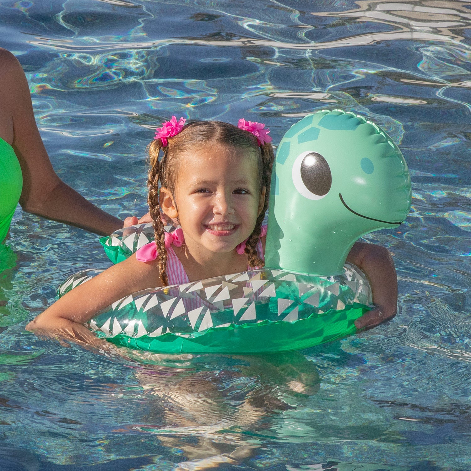 Child in a pool with a green inflatable turtle float
