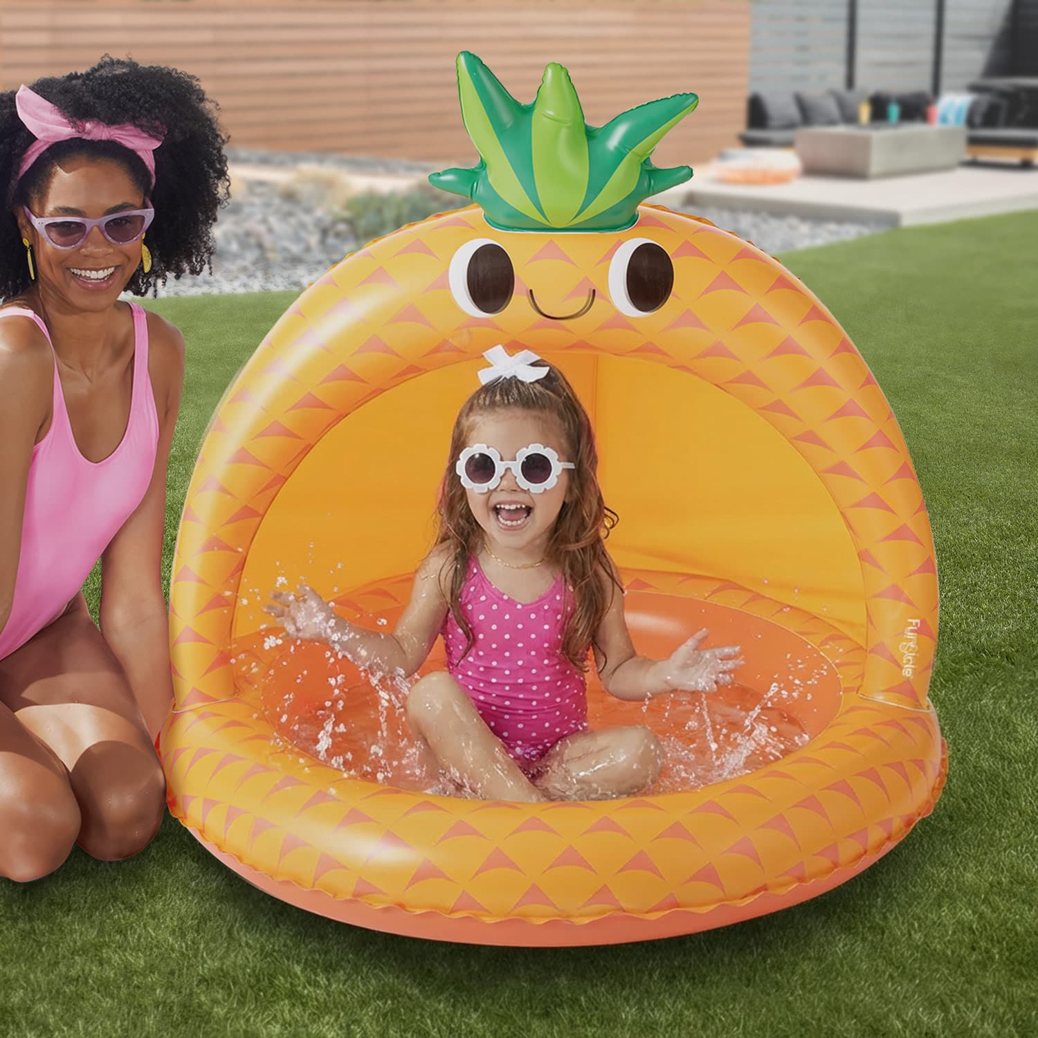 a child playing in a pineapple-shaped inflatable pool on grass.