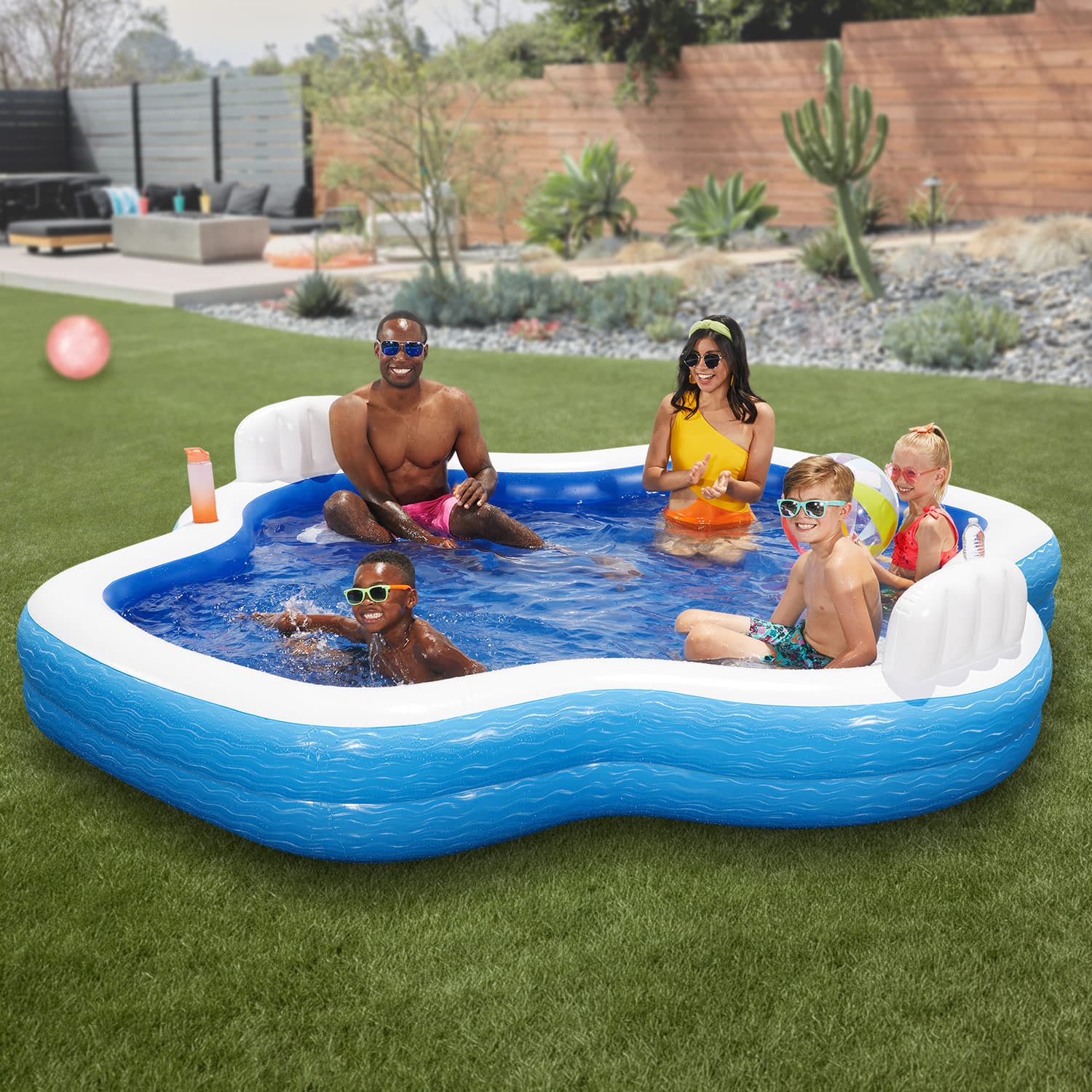 Family enjoying time in a heart-shaped inflatable pool outdoors.