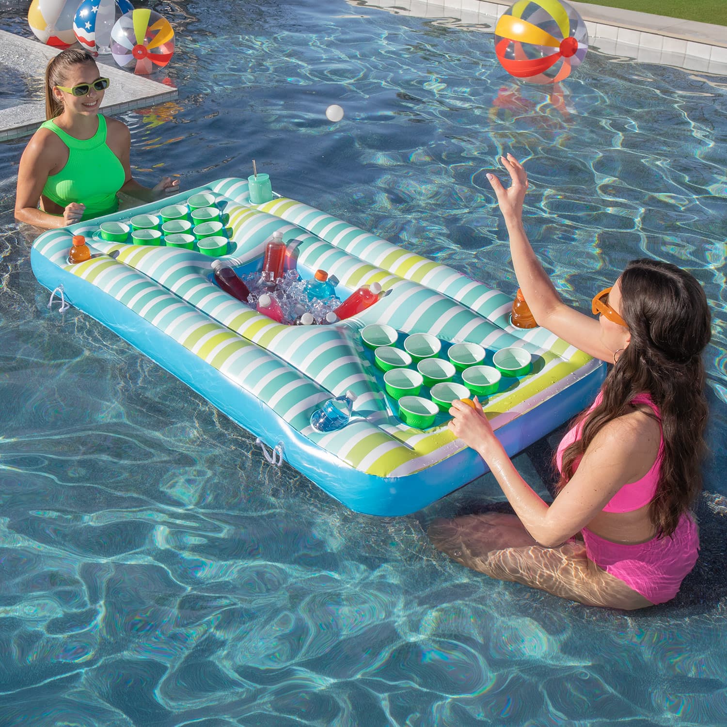 Two women playing with an inflatable pool table in a swimming pool.