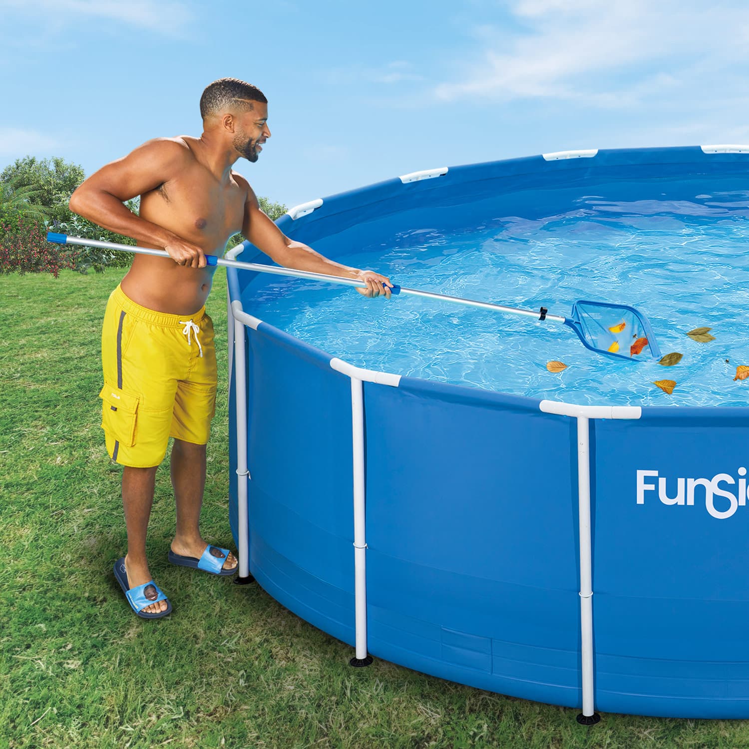 Man cleaning an above-ground pool with a skimmer net on a grassy lawn.