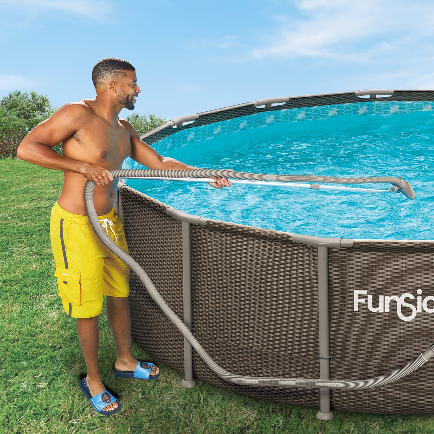 Man cleaning an above-ground pool with a hose, set against a clear blue sky.