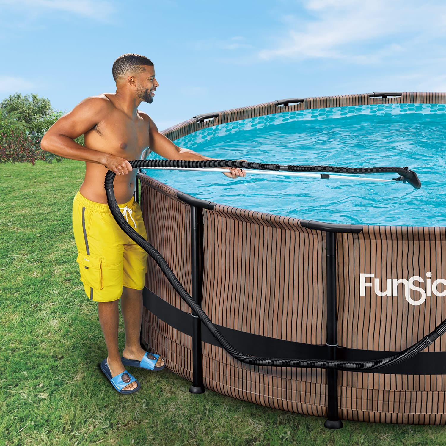 Man cleaning a pool with a vacuum hose, standing next to a Funsicle pool.