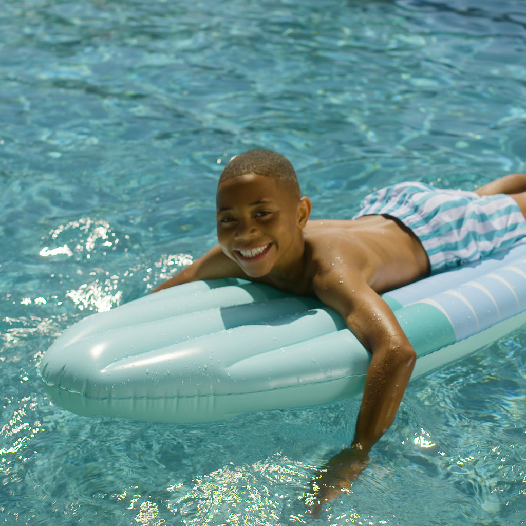 a boy riding Funsicle California Dreamin' Surfboard Float in a pool