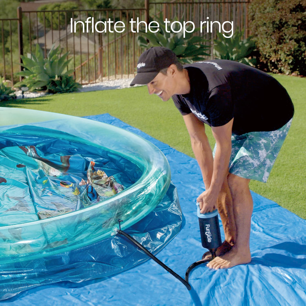 A man uses a hand pump to inflate the top ring of Funsicle 3D QuickSet Pool on a grassy backyard lawn.